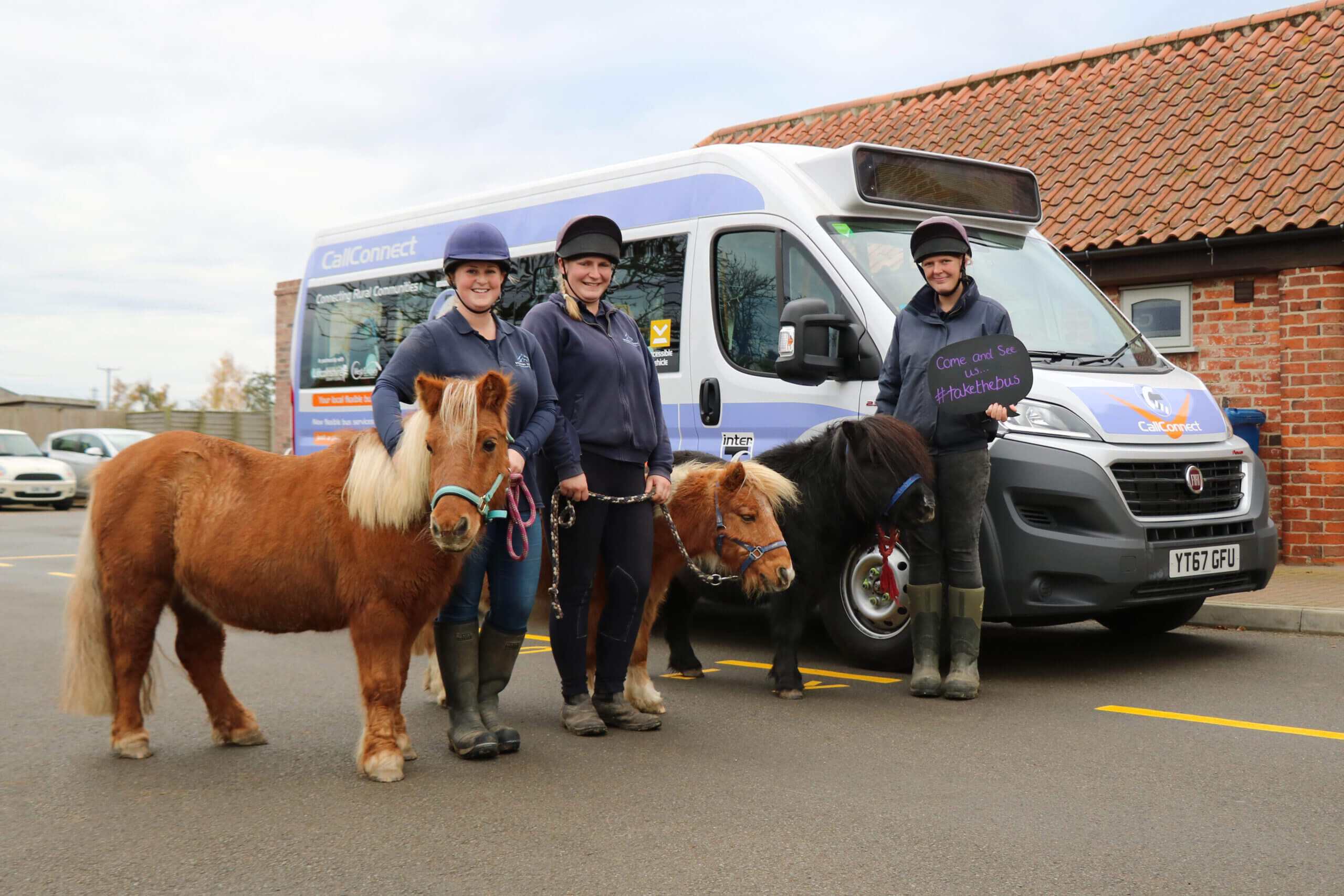 three shetland ponies with their handlers stood in front of a mini bus
