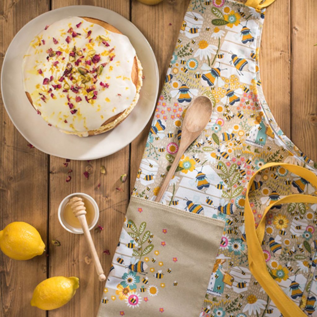 bee and floral patterned apron folded on kitchen table with various bits of food surrounding it