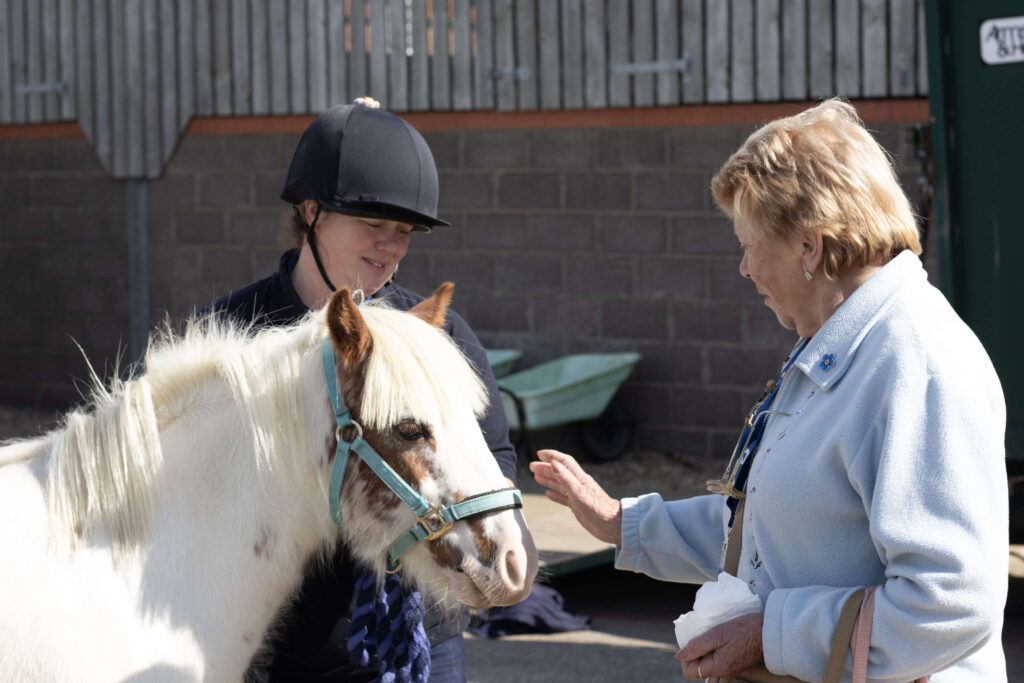 members of staff holding a pony stood with a visitor