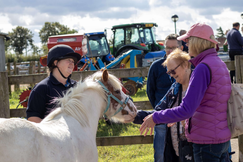 members of staff holding a pony stood with a visitor