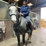 dappled grey pony with rider stood in a barn